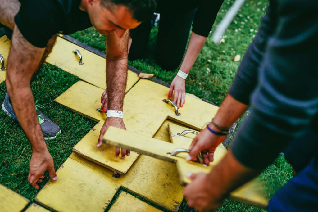 a group of people taking part in a team building challenge using wooden parts