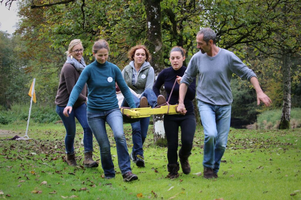 group of people carrying a wooden structure with someone on top during a team building event
