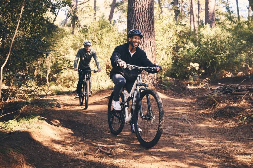 Two people riding electric bikes through the forest as part of a team-building activity.