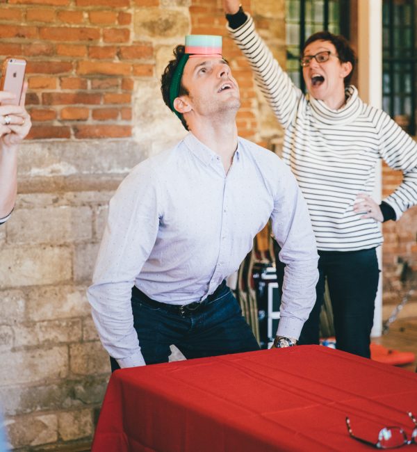 Balance challenge during a team building event where a participant tries to keep a box on his head