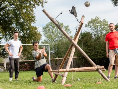personnes qui participent à un défi d'adresse avec une grande catapulte artisanale