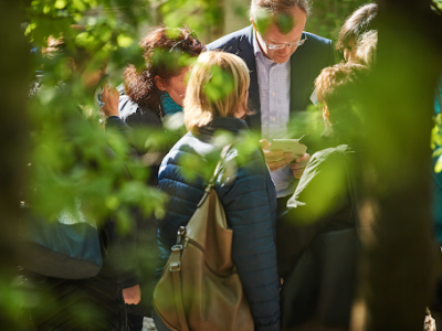 A group of people gathered around a tablet taking part in an interactive game in the nature